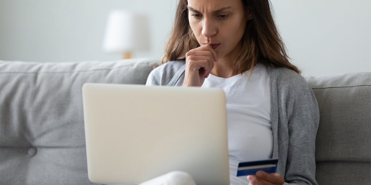 fakturasvindel bekymret kvinne med laptop og bankkort
